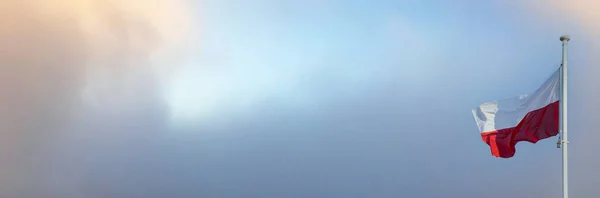 Государственный флаг Польши развевается на фоне голубого неба и персиковых облаков. Панорама. — стоковое фото