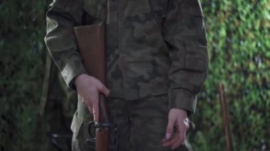Dişi bir asker tüfeğini doldurur ve parmağını tetiğe koyar..