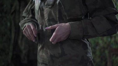 Üniformalı bir bayan asker askeri kemerini çözer..