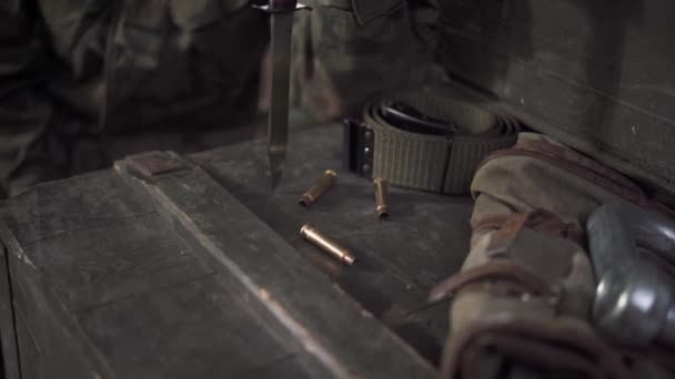 La soldado sostiene una bayoneta en su mano y golpea suavemente los casquillos del rifle.. — Vídeos de Stock