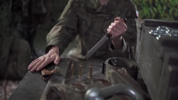 A female soldier bayonet turns over rifle casings. Dilemmas of decision making. — Stock Video