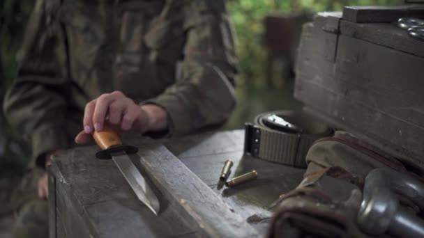 La femme soldat pose sa baïonnette et commence à empiler des douilles de fusil puis les renverse. — Video