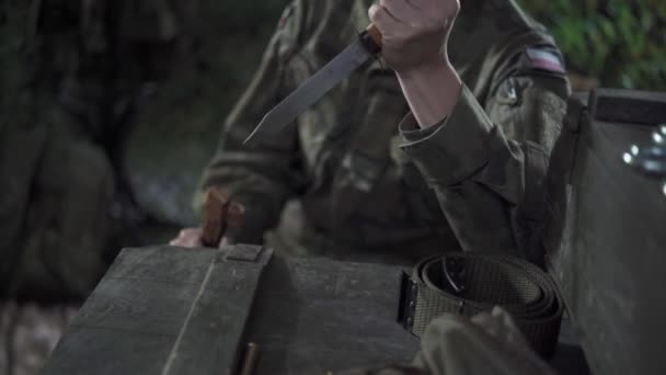 Um soldado enfia uma baioneta na tampa de uma caixa e gira-a. Escolhas difíceis no exército. — Vídeo de Stock