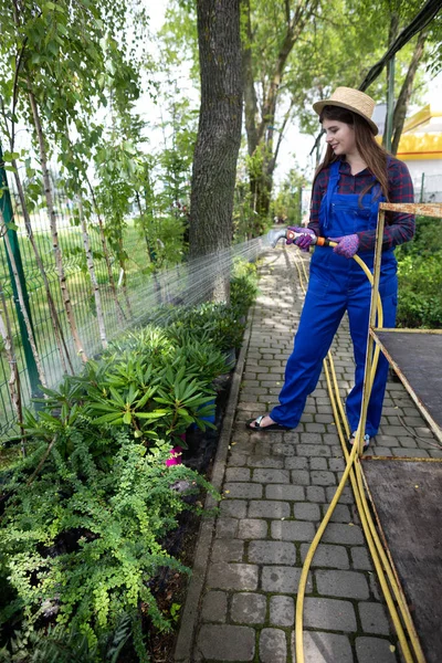 A worker waters tree seedlings in a garden store. — Stock Photo, Image