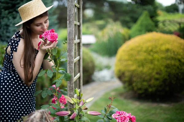 Una joven huele las rosas rosadas de su jardín. —  Fotos de Stock