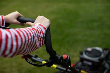 Elinde çim biçme makinesi tutan bir kızın yakın çekim görüntüsü..