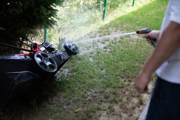 A lawn mower while being washed with a strong stream of water. — Stock Photo, Image