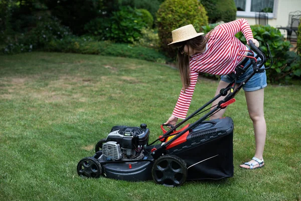 The girl pulls the lever from the manual start of the garden mower. — Stock Photo, Image