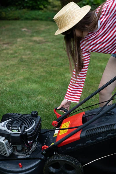 The girl pulls the lever from the manual start of the garden mower. — Stock Photo, Image