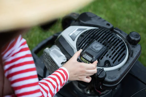 Close-up view of a woman removing the battery from a garden mower. — Stock Photo, Image
