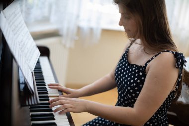 Genç bir kadın evinde özel olarak piyano çalar..