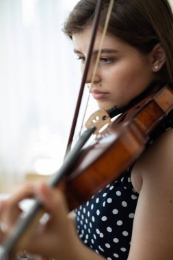 Evinin mahremiyetinde keman çalan genç bir kadının yakın çekimi..