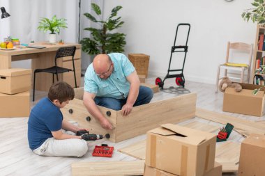 Babam katlanan bir kitaplığa bir mobilya vidası koyar..