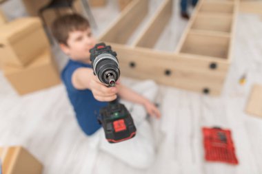 Genç bir çocuk önünde kablosuz bir tornavida tutuyor..