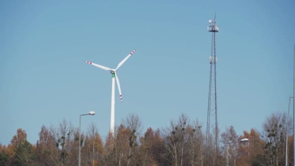 Looping. Windkraftanlage auf einem Hügel zwischen Bäumen. Sendemast für Mobilfunk. — Stockvideo
