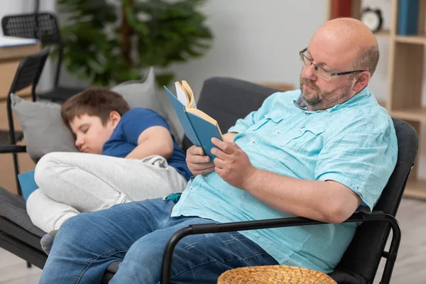 Батько читає книжку, а син засинає під час читання.. — стокове фото