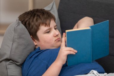 Yaslanan genç bir çocuk okulda kitap okuyor..