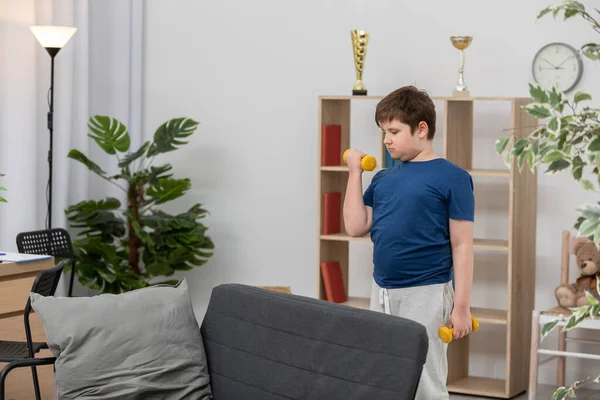 Um menino treina com halteres para a saúde. — Fotografia de Stock