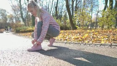 Genç bir kadın sabah koşusundan önce ayakkabılarını düzeltir..