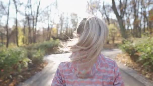 Une fille court dans l'allée d'un parc par une journée ensoleillée. — Video