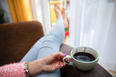 Bir kadının eli büyük bir bardak taze kahveyi tutar..