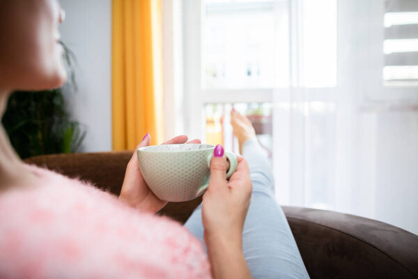 A womans hand holds a large mug of fresh coffee.