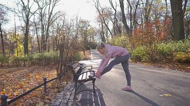 Enquanto correndo de manhã, a menina estica os músculos da perna. — Vídeo de Stock