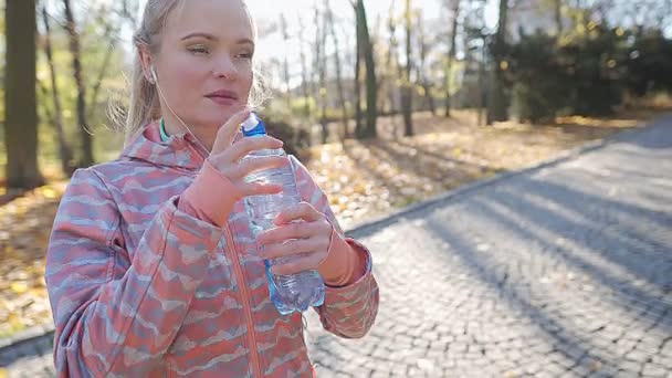 Молодая женщина пьет воду из бутылки во время перерыва. — стоковое видео