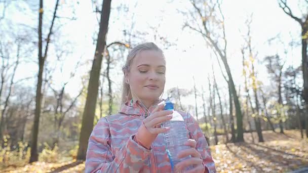 O fată ia o pauză de la alergarea de dimineață pentru a bea apă. — Videoclip de stoc