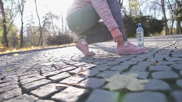 En flicka korrigerar sina skor och strumpor innan morgonen joggar. — Stockvideo