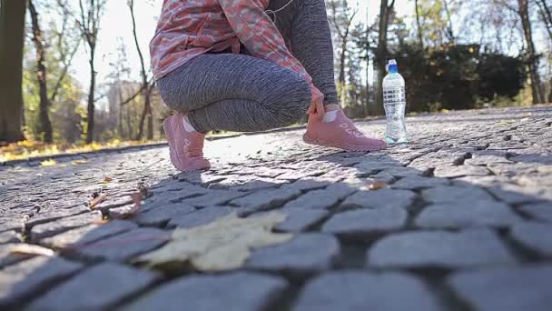 Une femme ajuste ses chaussures et ses chaussettes avant son jogging matinal. — Video