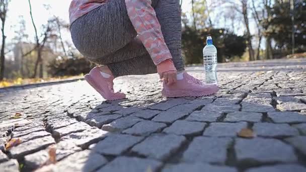 Une femme ajuste ses chaussures et ses chaussettes avant son jogging matinal. — Video