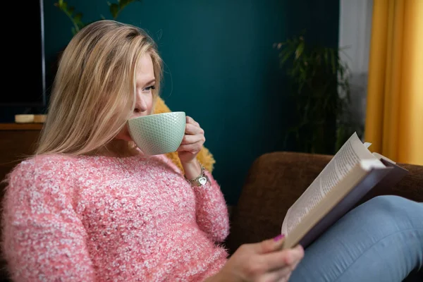 Дівчина відпочиває, читаючи книгу і п'ючи каву . — стокове фото