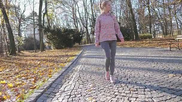 V městském parku si dívka protáhne svaly na nohách.. — Stock video