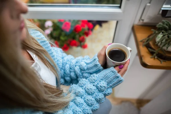 A woman warms her frozen hands against a mug of hot coffee. — Stock Photo, Image