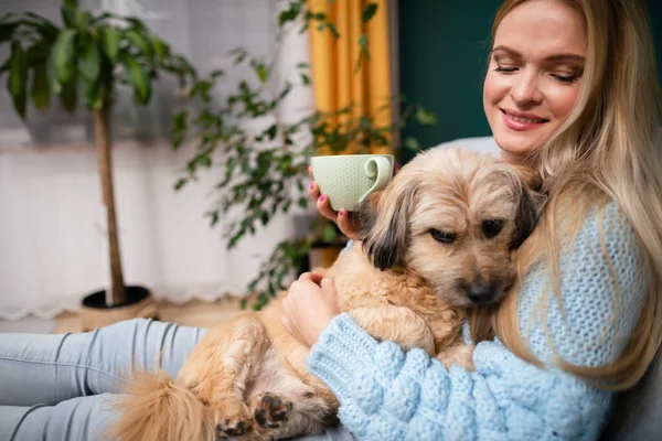 Genç bir kız, kahve içme ayini sırasında köpeğine sarılıyor..