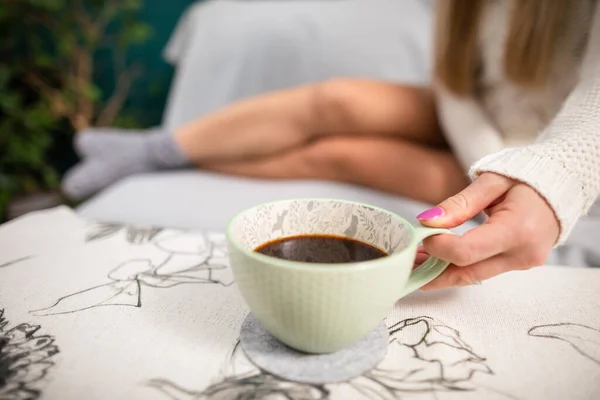 As pernas magras de uma menina sexy. Ela está segurando uma xícara de café quente. — Fotografia de Stock