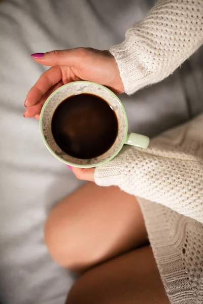Pernas femininas arrumadas no sofá. Vista de perto de uma xícara de café enquanto relaxa. — Fotografia de Stock