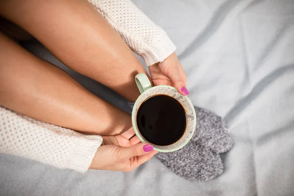Uma chávena de café nas mãos de uma mulher. Pernas limpas. — Fotografia de Stock