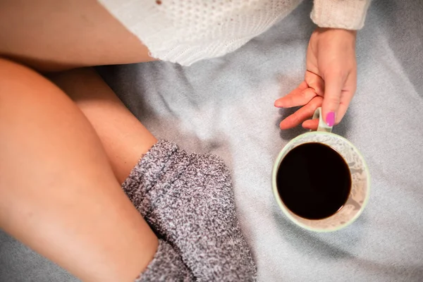 Vista de perto de uma xícara de café. Pernas femininas finas em meias de lã. — Fotografia de Stock