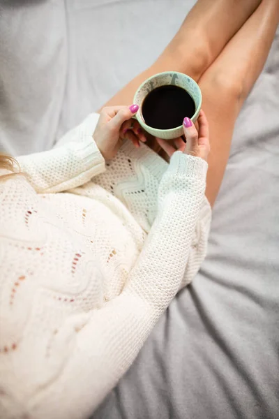 Uma mulher com pernas bem torneadas segura uma xícara de café. — Fotografia de Stock