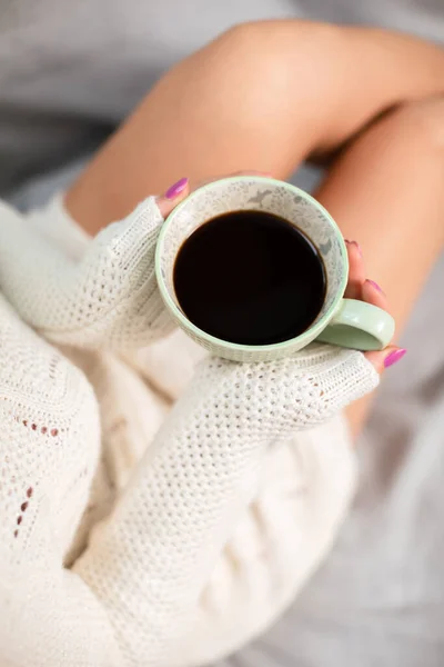 Uma mulher com uma camisola segura uma xícara de café suavemente. — Fotografia de Stock