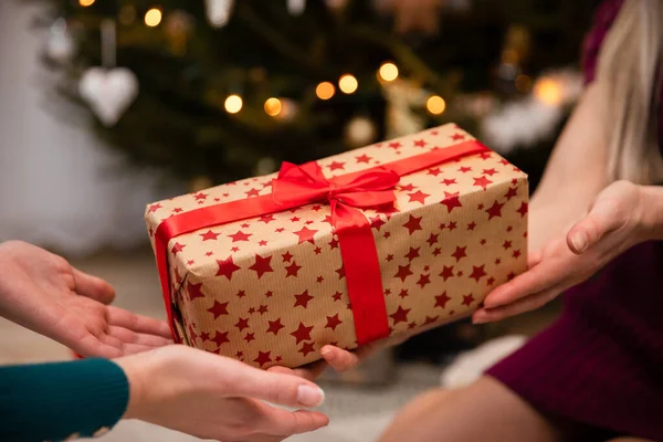 Közelkép megtekintése, miközben egy ajándék egy piros íj karácsonykor. — Stock Fotó