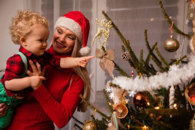 Bir anne iki yaşındaki bir çocuğu kollarında tutar ve bir yayı işaret eder..