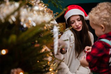 Küçük bir çocuk Noel ağacına nasıl süs asılacağını merak ediyor..