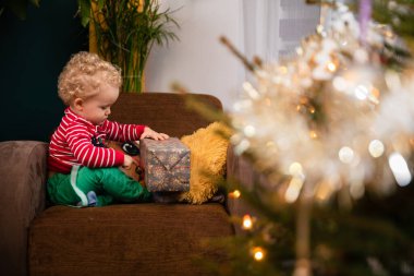 Noel günü, bir çocuk sandalyeye oturur ve hediyesini açar..