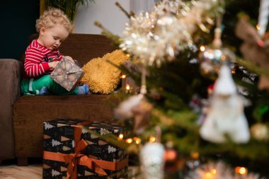 Noel günü, bir çocuk sandalyeye oturur ve hediyesini açar..