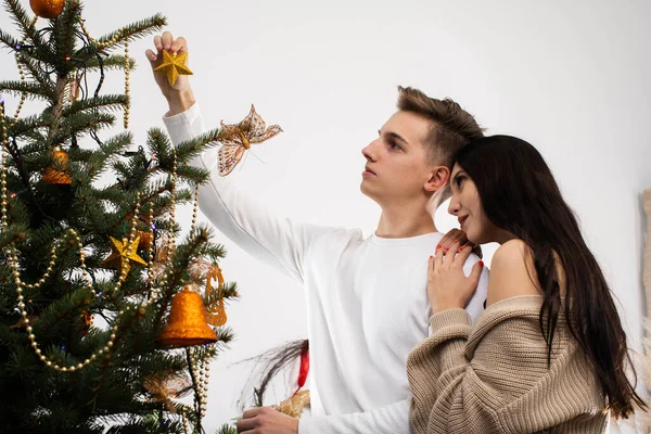 Planeando una pareja enamorada para poner una estrella dorada en la parte superior del árbol de Navidad. La decoración del árbol decorativo para la Navidad. — Foto de Stock