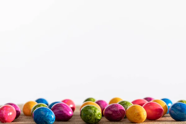 Ovos de Páscoa coloridos dispostos em tecido de linho e fundo branco. Páscoa. — Fotografia de Stock