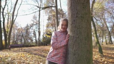 Tatmin olmuş bir sarışın büyük bir ağacın yanında duruyor ve ona hayran..